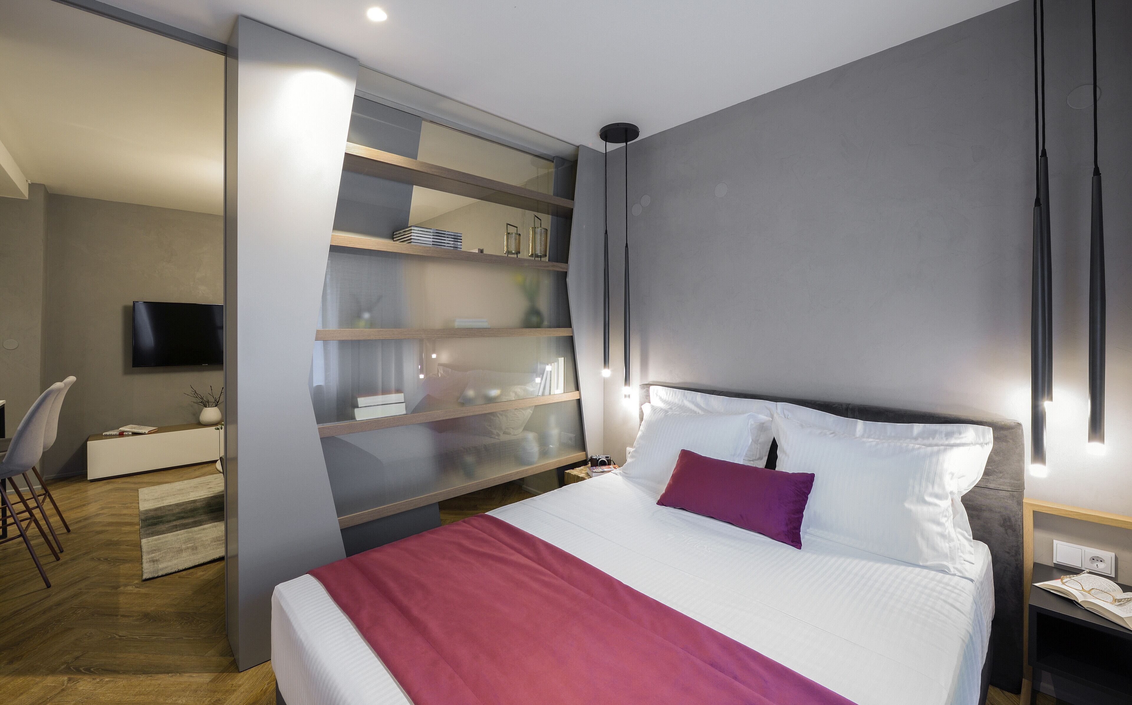 Un dormitorio moderno con una cama, un televisor, un escritorio y una estantería.
