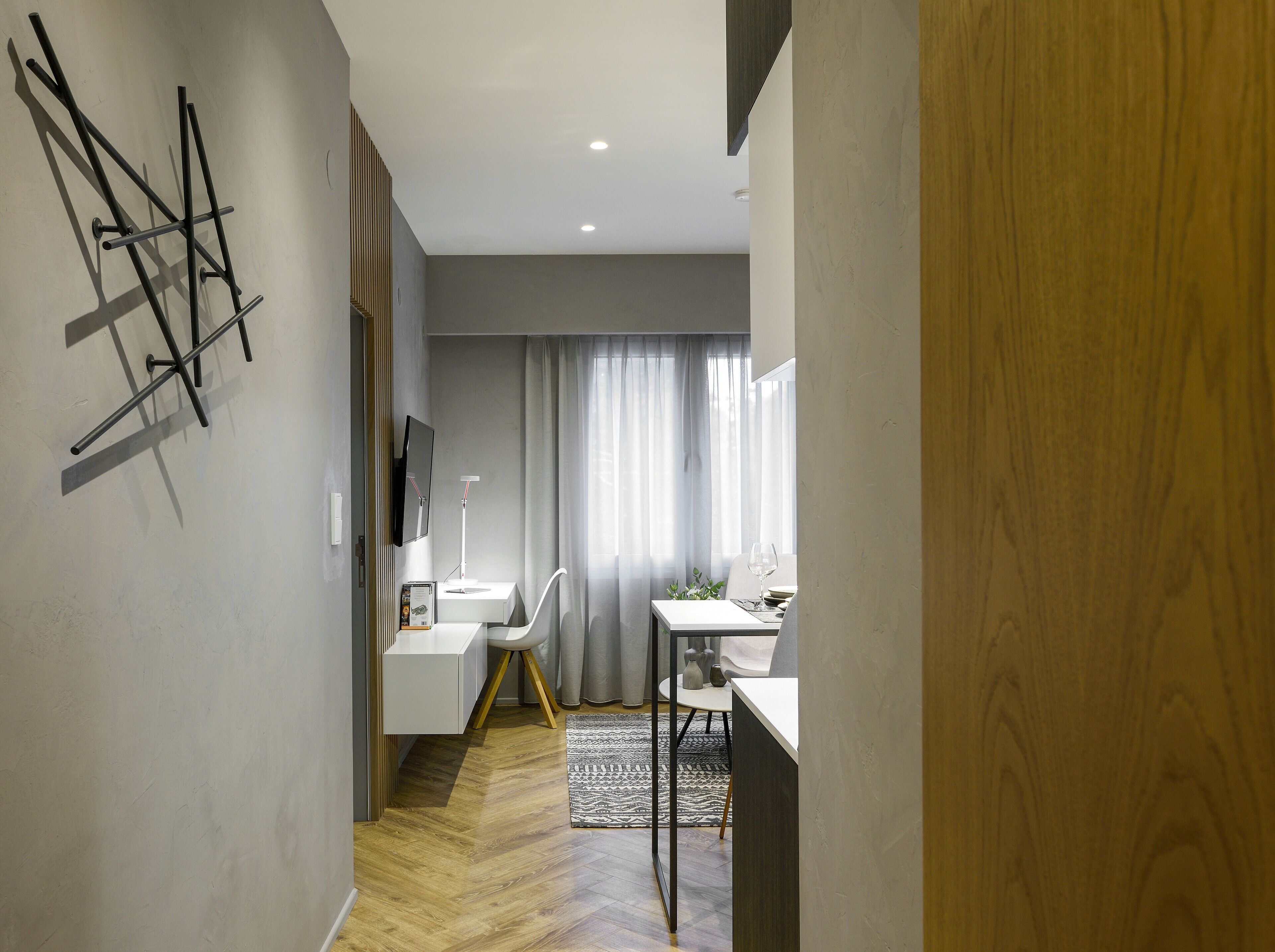 Ein modernes Interieur mit Holzboden, weißem Schreibtisch, Stuhl und einem kleinen Tisch mit einem Glas.
