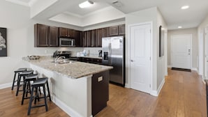 Una cocina moderna con una isla central, armarios de madera oscura, electrodomésticos de acero inoxidable y piso de madera.