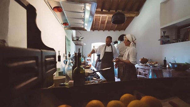 Une cuisine avec un plafond en bois, un poêle et divers ustensiles de cuisine. On voit des oranges au premier plan.