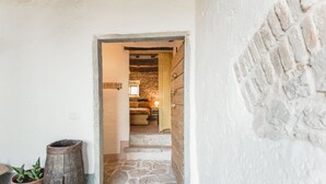 Un escalier en pierre mène à une pièce dont un des murs est en pierre et qui possède une fenêtre.