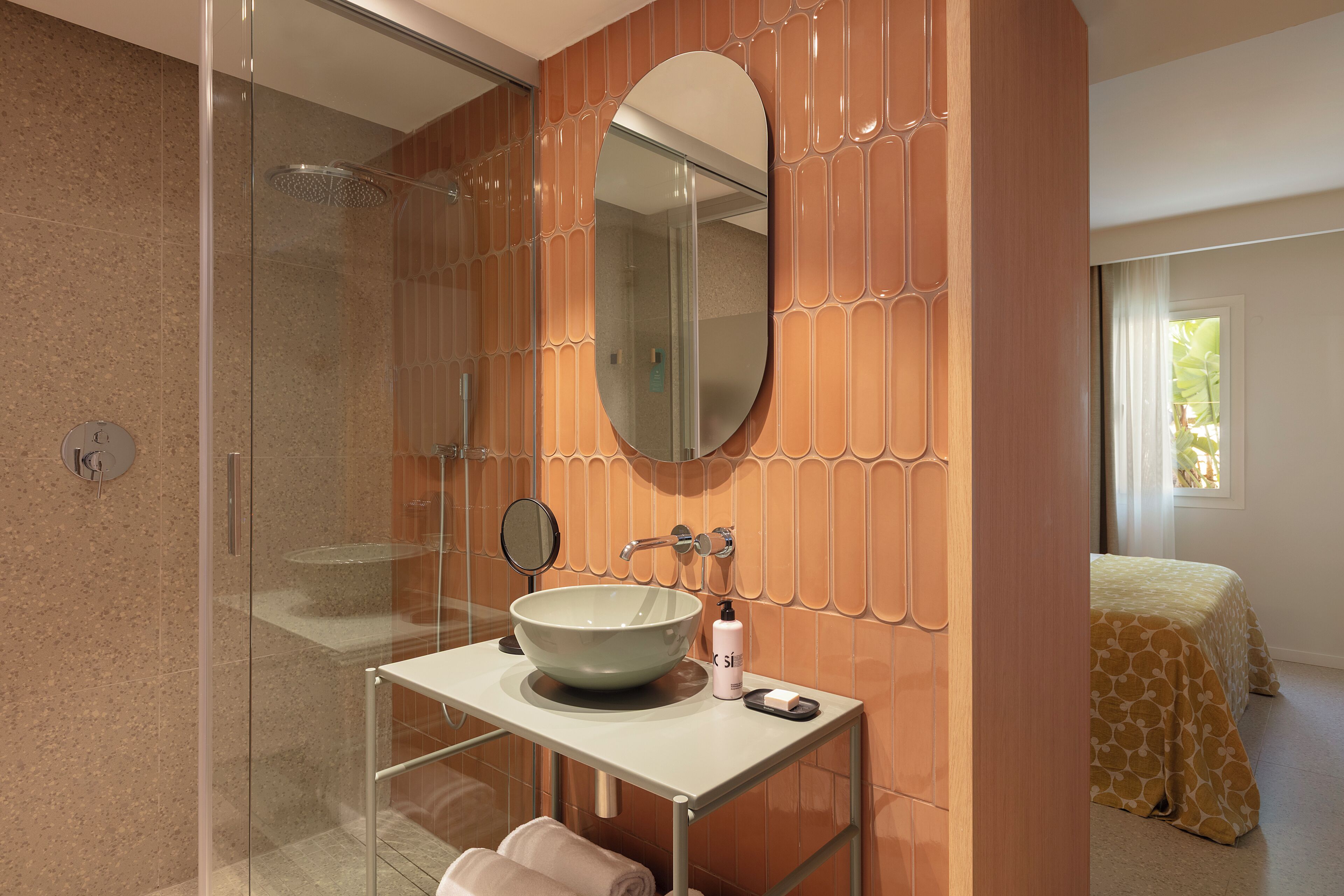A bathroom with a glass shower enclosure, a white sink with a large basin, a mirror, and a towel rack.
