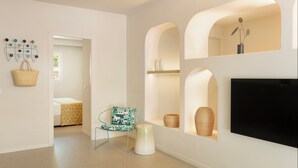 Un intérieur moderne avec un téléviseur à écran plat, un panier en osier, une chaise à motifs et une petite table.