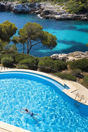 Una piscina techada, una piscina al aire libre, sombrillas