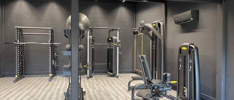 Une salle de sport moderne équipée de divers appareils d’entraînement, notamment un support à squat, une machine à câbles et un banc de musculation.