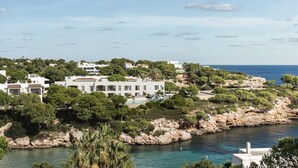 Une propriété située sur la côte, avec un bâtiment blanc entouré de verdure et d’un terrain rocheux.