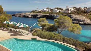 Una piscina techada, una piscina al aire libre, sombrillas