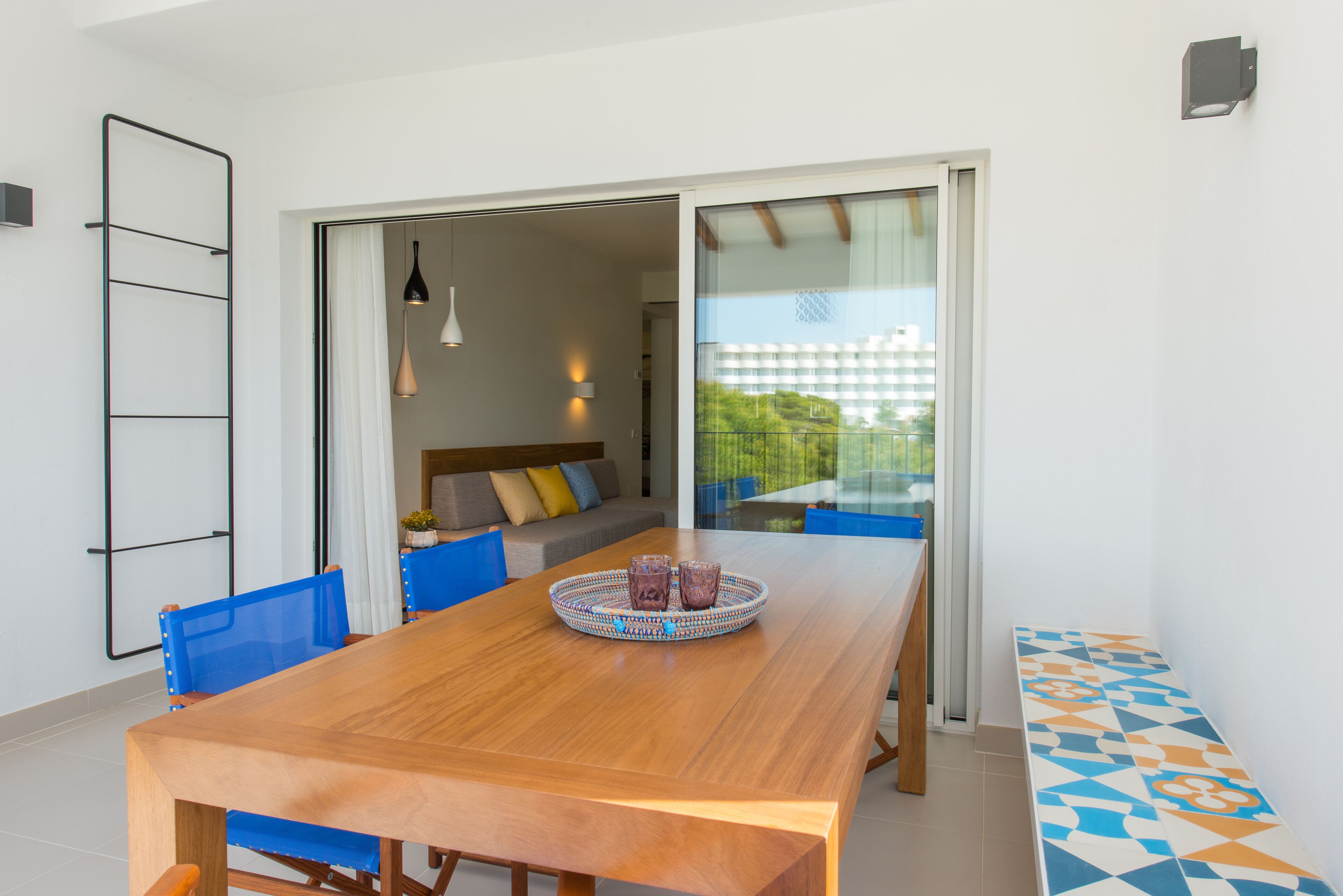 A dining area with a wooden table, blue chairs, and a tray with glasses.