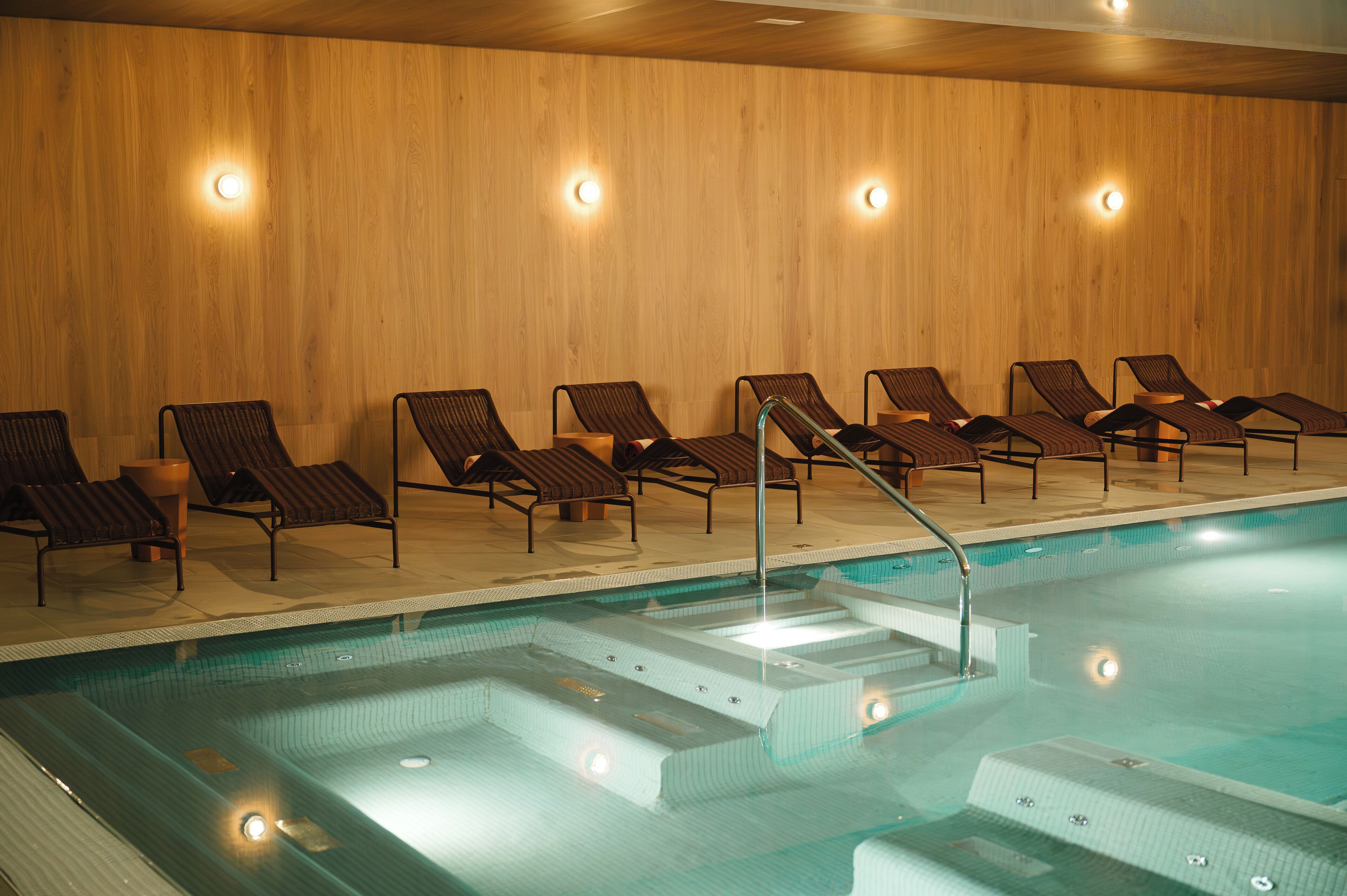 Une piscine dotée de chaises longues et de marches permettant d’y accéder facilement.