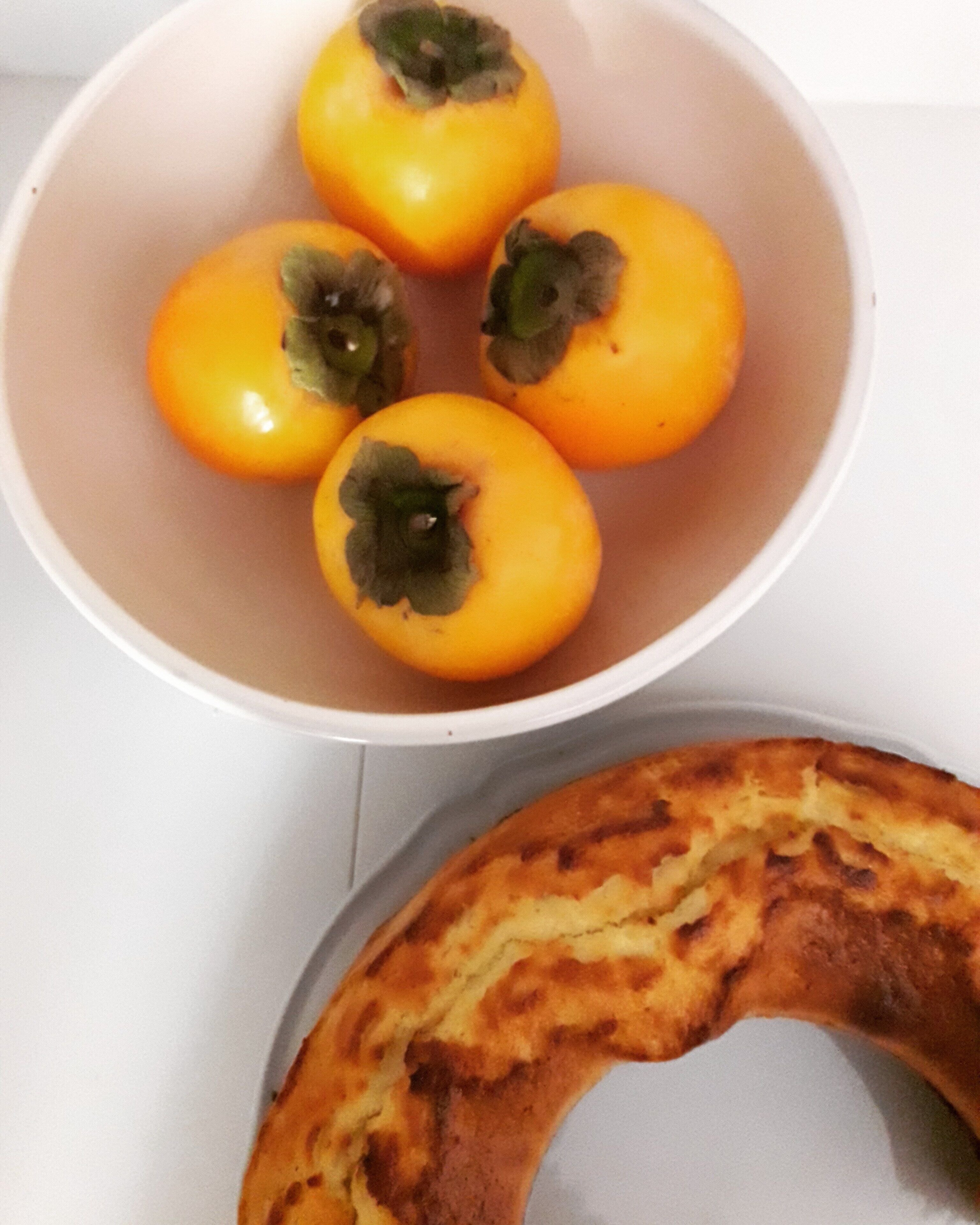 A bowl of yellow tomatoes with dark spots on a white surface.