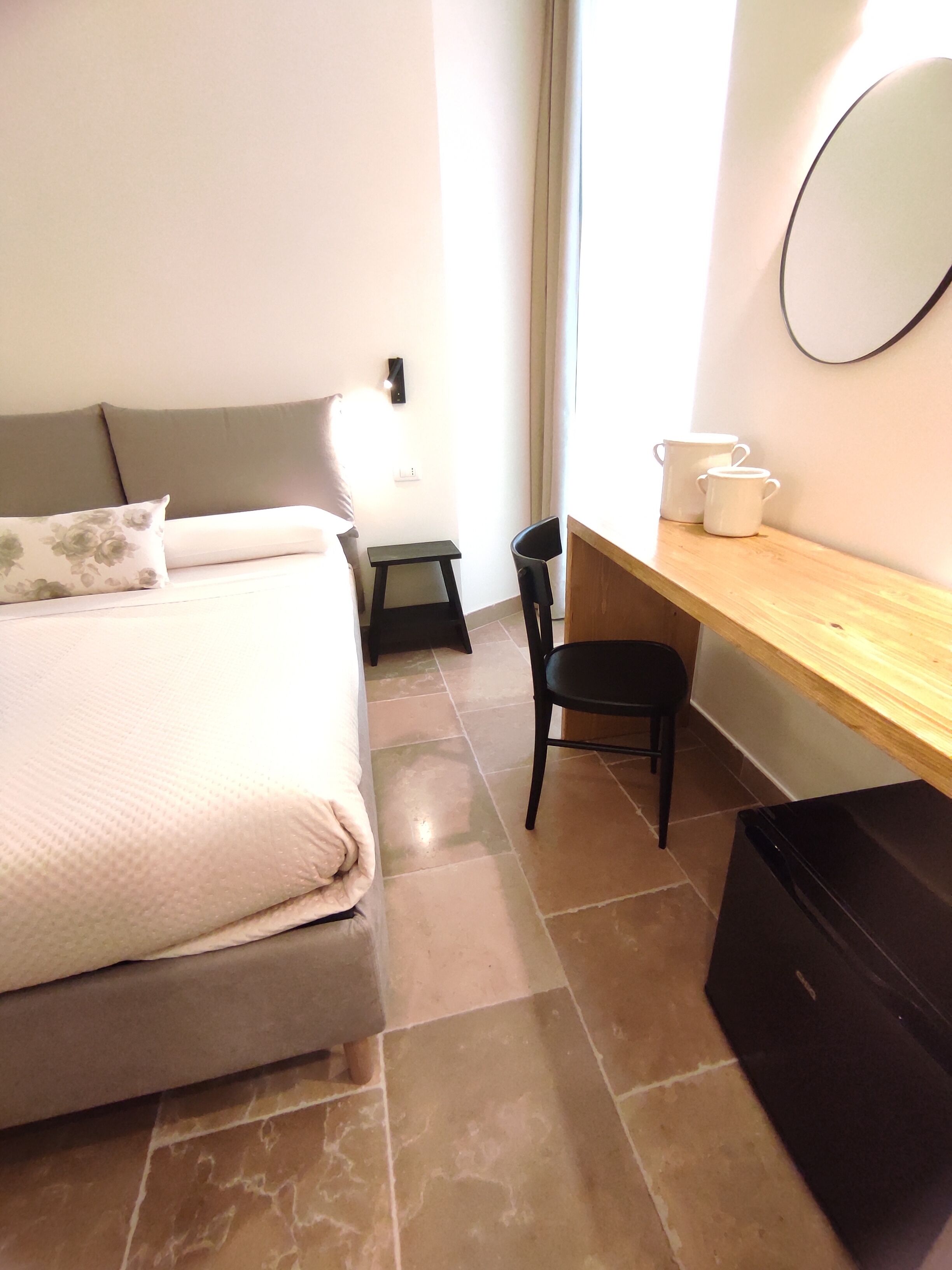 A bedroom with a bed, a desk, a chair, and a mirror.