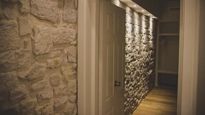 Un pasillo con pared de piedra y una puerta que da a una habitación.