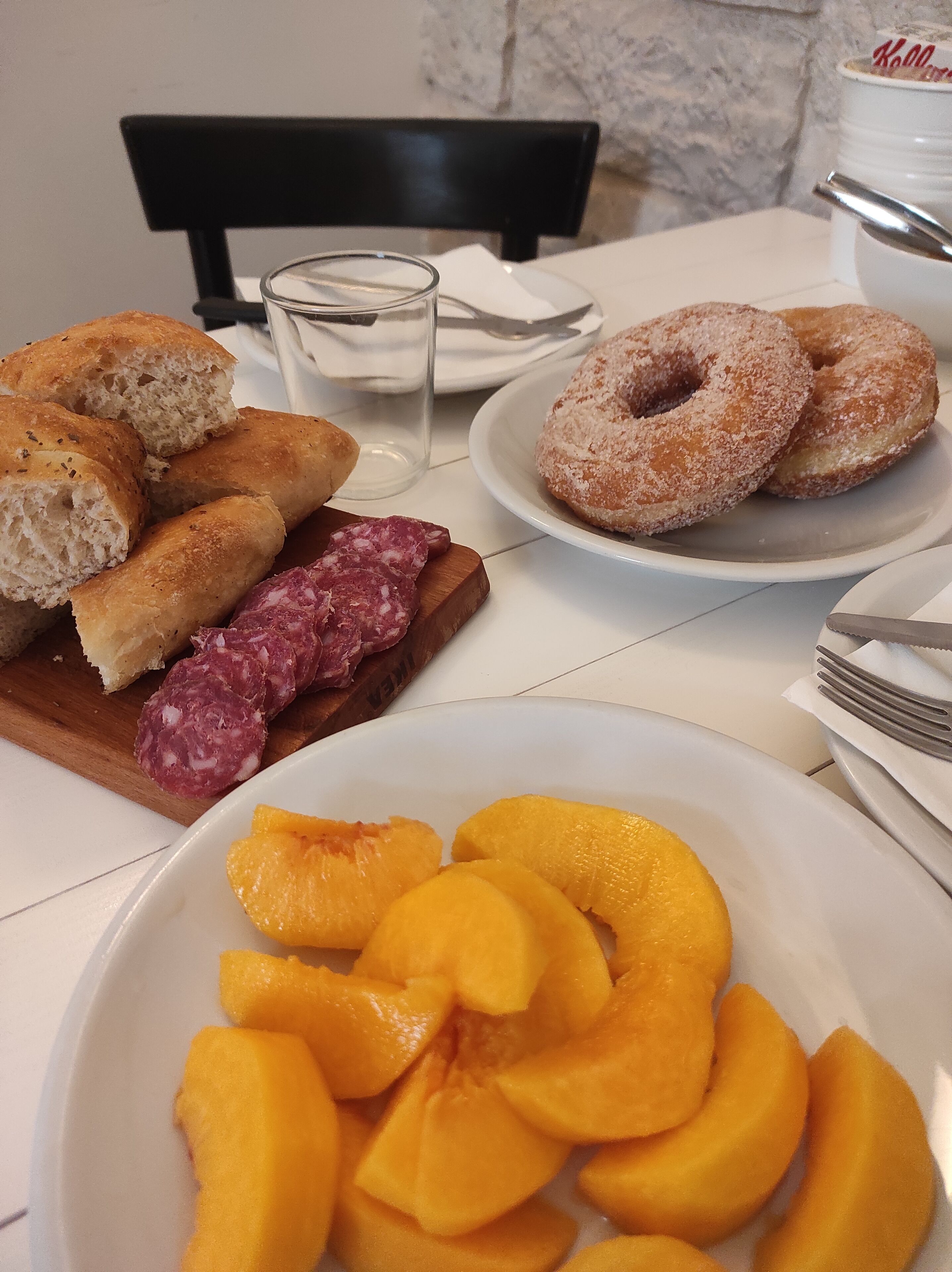Une table sur laquelle se trouvent des assiettes remplies de nourriture, notamment du pain, des beignets et des tranches de pêches.