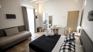 Una habitación de hotel con cama, sofá, escritorio y espejo.