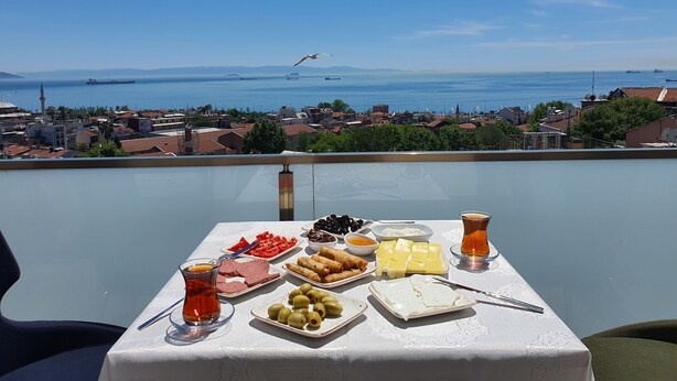 Une table dressée avec de la nourriture et des boissons sur un balcon donnant sur une ville et la mer.