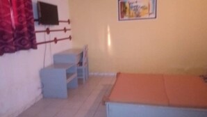Una habitació petita amb un llit, un escriptori i una cadira.