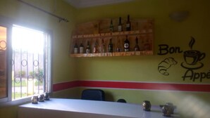 Interior d'una cafeteria amb barra, una finestra que ofereix una vista i una paret decorada amb una il·lustració de tassa de cafè i croissant.