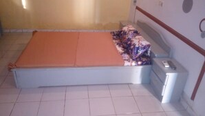 Habitació petita amb un llit individual, una taula de nit i un calefactor fixat a la paret.