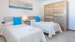 Une chambre d’hôtel avec deux lits, une armoire, un tableau et un lustre.