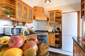 A kitchen with wooden cabinets, a microwave, an oven, and a refrigerator.