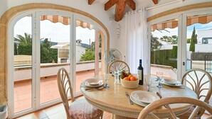 Un coin repas avec une table ronde, des chaises et un ventilateur.