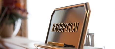 Un mostrador de recepción con la palabra 'RECEPTION' escrita, ubicado sobre una superficie de madera.
