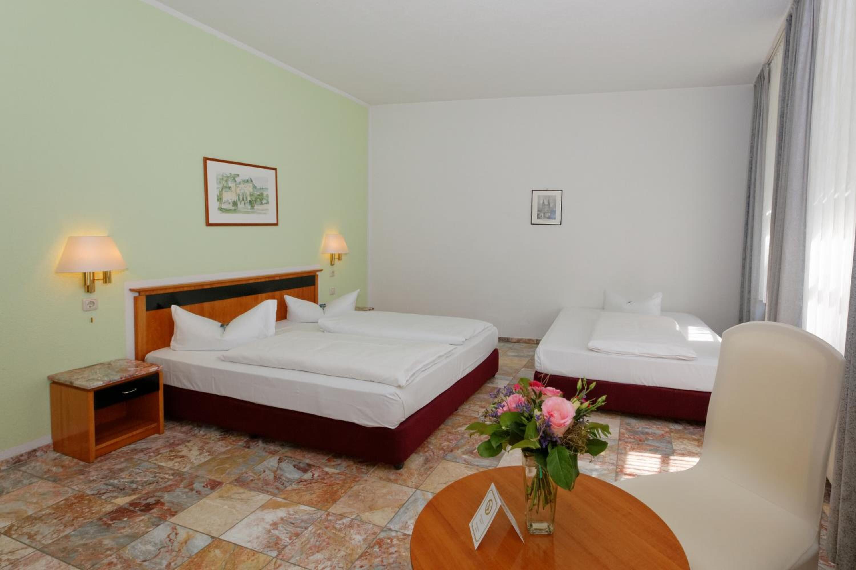 Una camera d'albergo con due letti, un comodino, una scrivania e una sedia.