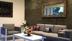 A modern living room with a grey sofa, a white coffee table, and a painting on the wall. - IOOVE Tanjung Seminyak Suites (Seminyak)