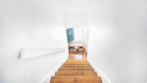 Una escalera estrecha que lleva a una habitación con ventana y puerta.