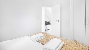 Una habitación de hotel con una cama, un armario y una puerta que da a un baño.