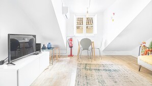 Un loft moderno con televisor, zona de estar y ventana con espacio de almacenamiento.