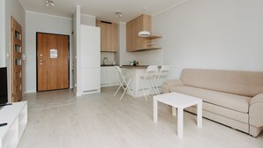 Een modern appartement met keuken, eethoek en woonkamer. Het heeft een bank, een eettafel en een televisie.