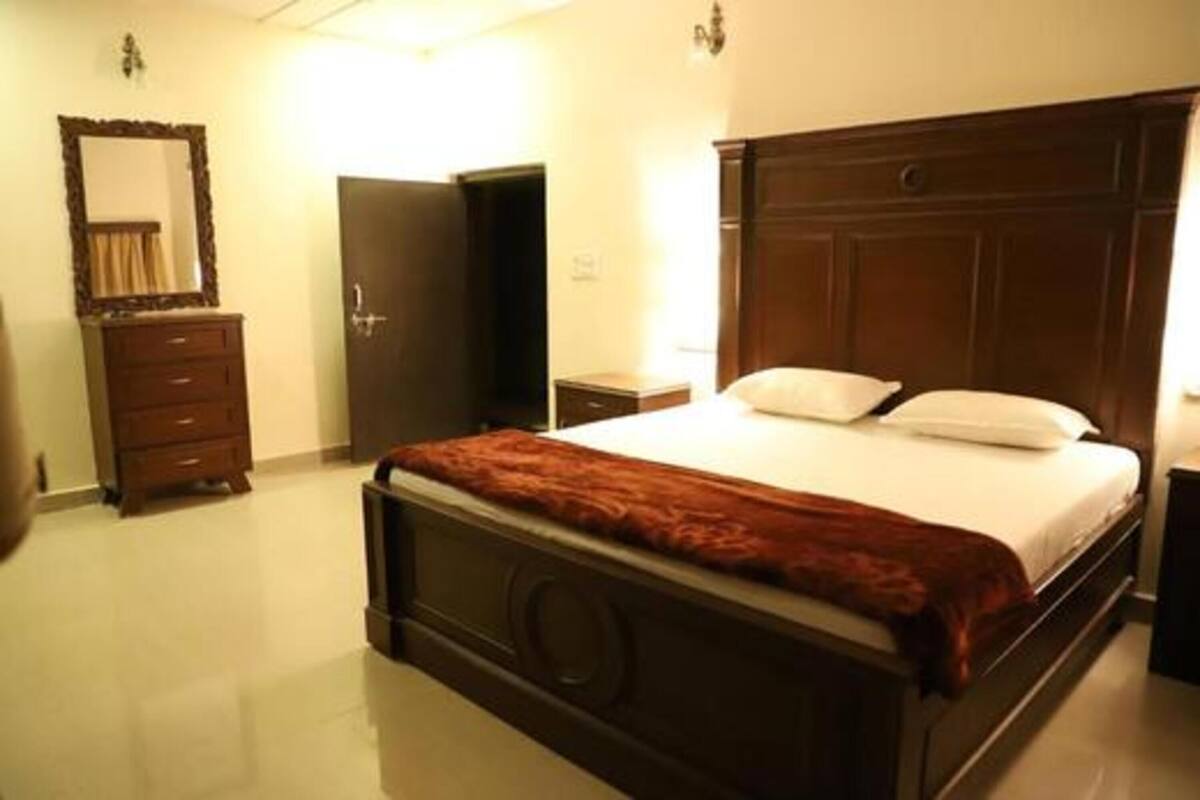 A bedroom with a wooden bed, a dresser, a mirror, and a door.