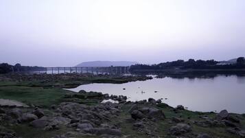 A serene lakeside landscape with a bridge, rocky shore, and distant hills.