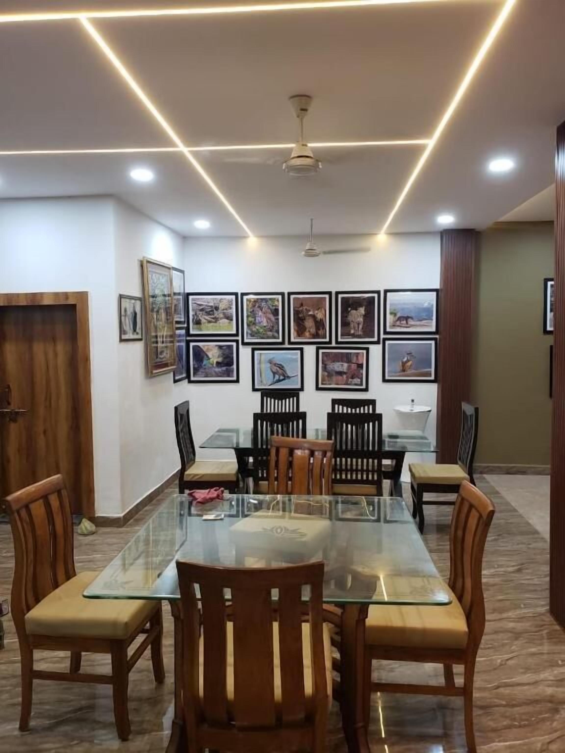 Un salón de conferencias con una mesa de vidrio, sillas de madera, cuadros en la pared e iluminación empotrada en el techo.
