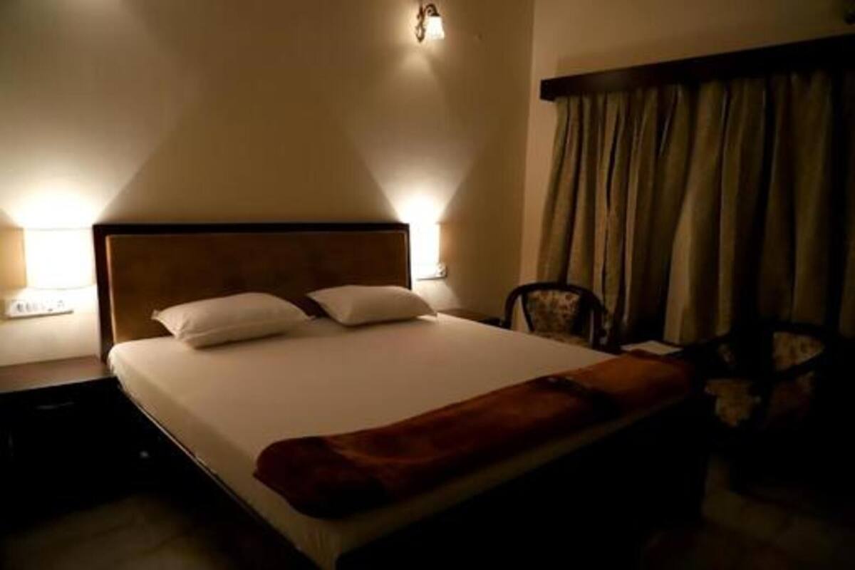 A hotel room with a bed, a nightstand, a lamp, and a chair.