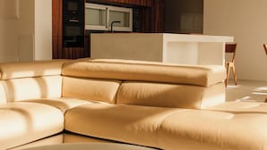 A modern living room with a beige sectional sofa, a round coffee table, and a kitchen area in the background. - Sea La Vie – Ocean-View Villa with Private Pool, Sunset Terrace and Privacy (Costa Adeje Tenerife)