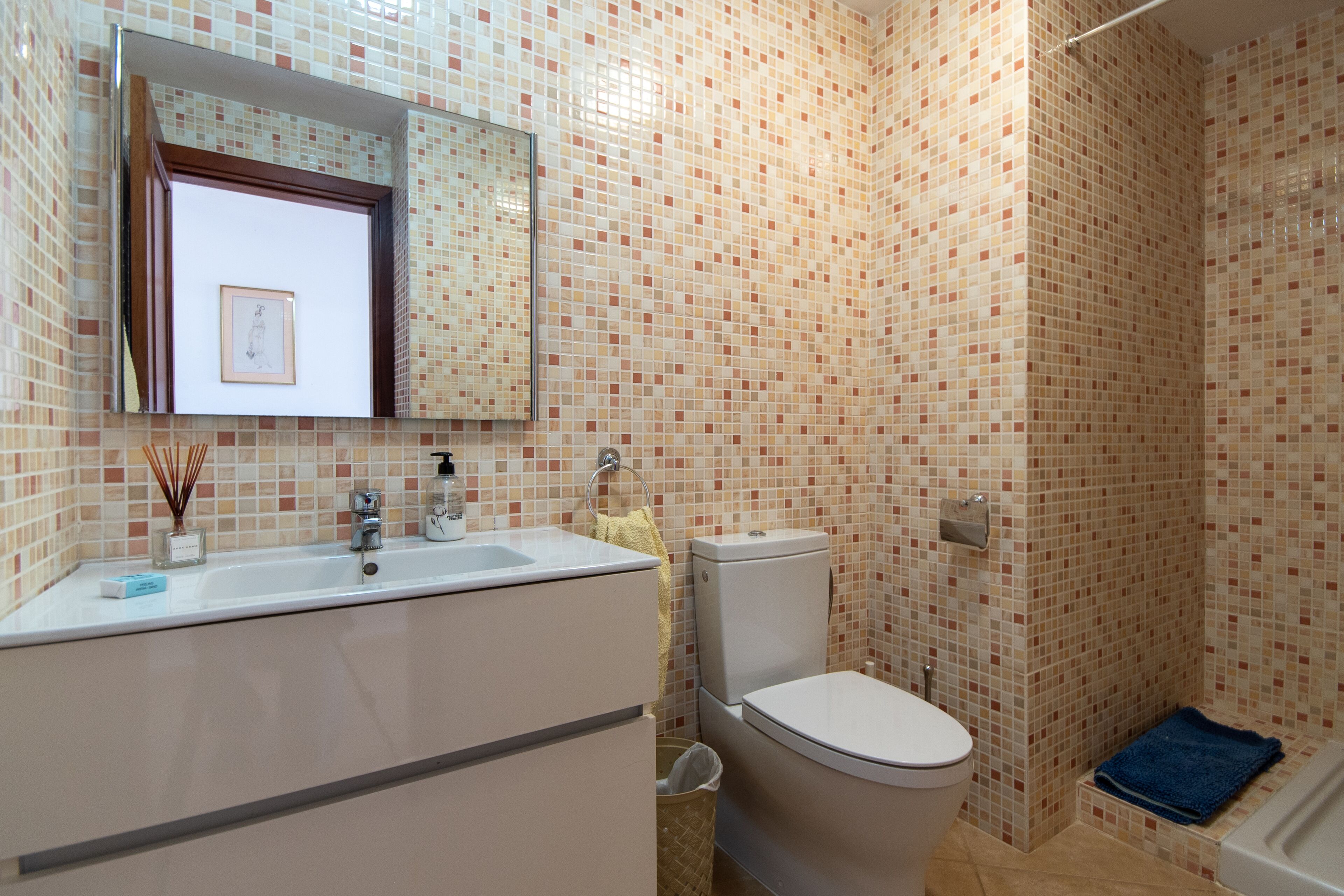 A bathroom with a tiled wall, a sink, a toilet, and a bathtub.