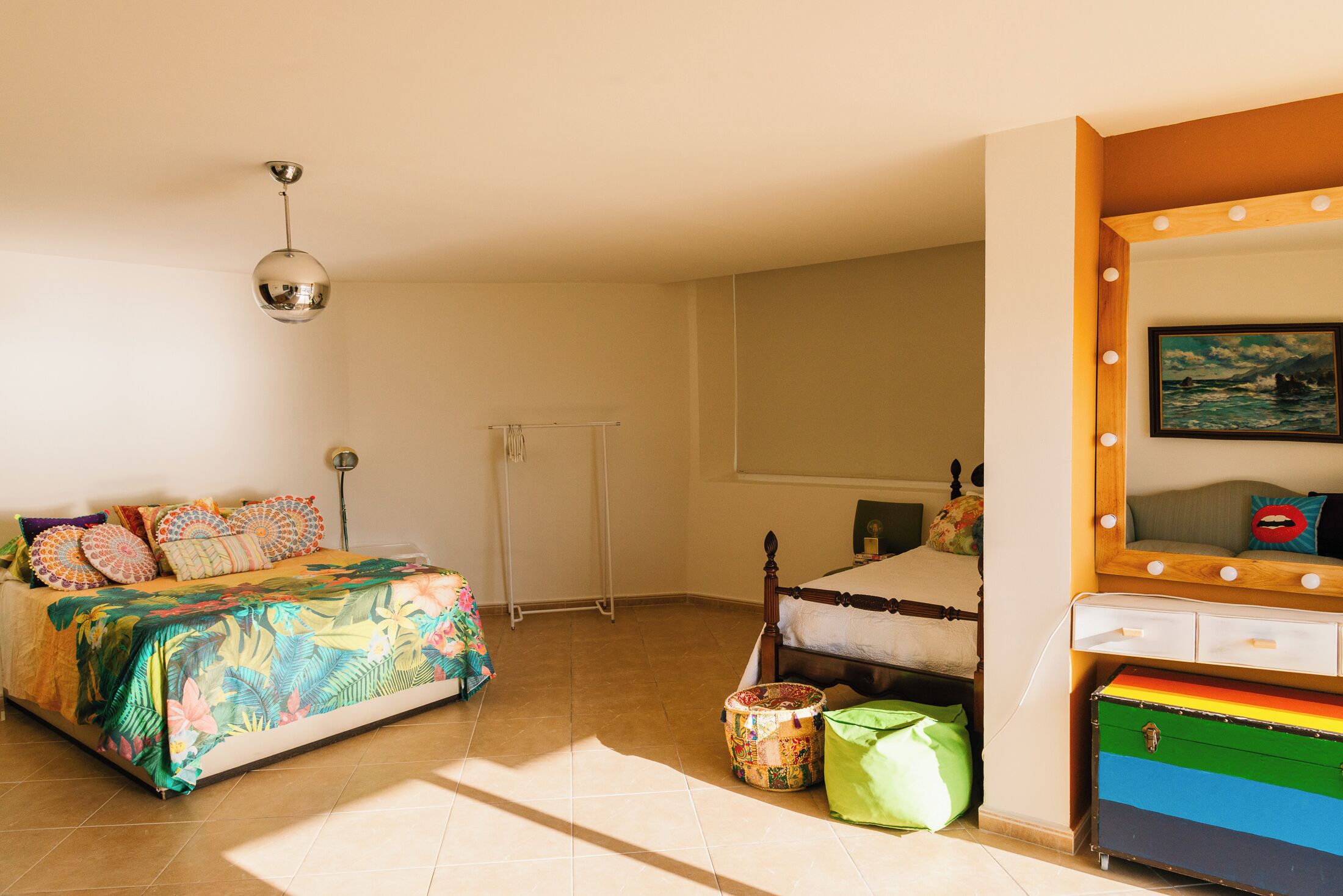 A bedroom with a bed, a dresser, a mirror, and a window.