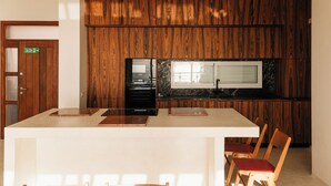 A modern kitchen with wooden paneling, a built-in stove, and a window with blinds. - Sea La Vie – Ocean-View Villa with Private Pool, Sunset Terrace and Privacy (Costa Adeje Tenerife)