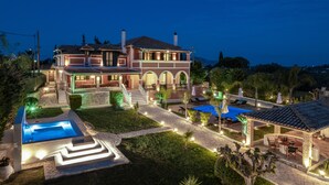 A large, multi-story house with a swimming pool, outdoor seating, and a well-lit garden. - Amalthia Villa (Zakynthos)