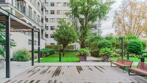 Une cour avec une terrasse en bois, des bancs et de la verdure.