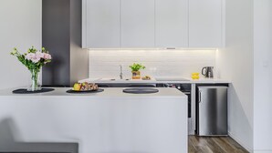 Une cuisine moderne avec des meubles blancs, un évier encastré et un réfrigérateur compact.