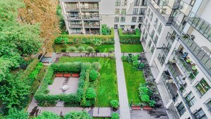 Un immeuble résidentiel de grande hauteur doté de nombreux balcons, d’une cour intérieure aménagée en espace vert et d’un espace de stationnement pour vélos.