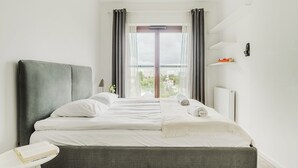 Une chambre d’hôtel moderne avec un grand lit, une table de chevet, une fenêtre avec des rideaux et une vue sur la ville.