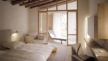 Un dormitorio con cama, una silla, un escritorio y un ventanal amplio.