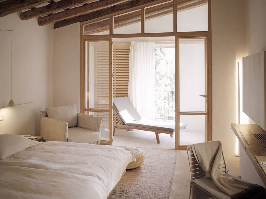 Un dormitorio con cama, una silla, un escritorio y un ventanal amplio.