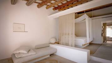 A bedroom with a wooden ceiling, a bed with a canopy, a sofa, and a small decorative item on the floor.