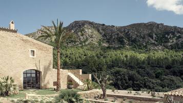 Un edificio con fachada de piedra, una gran entrada en arco y una escalera que lleva a una terraza.