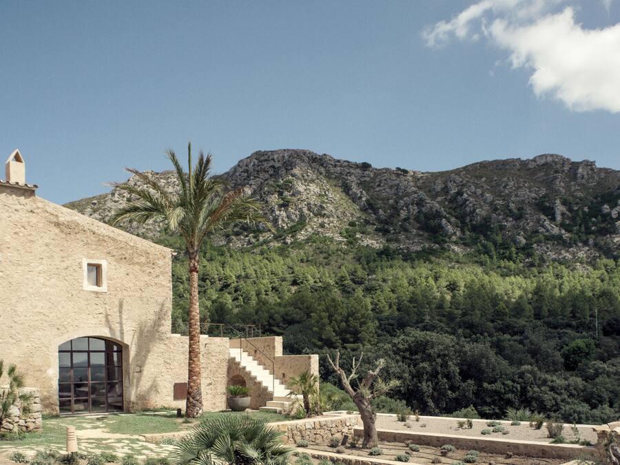 Un edificio con fachada de piedra, una gran entrada en arco y una escalera que lleva a una terraza.
